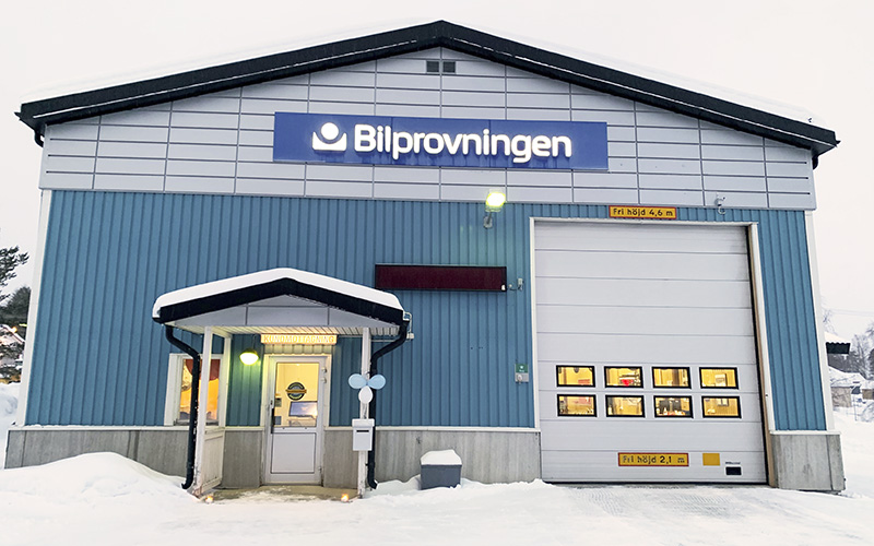 Exteriör bild av Bilprovningens station i Övertorneå. Fasaden är blå och vid dörren hänger ballonger. Det ligger snö på marken. 