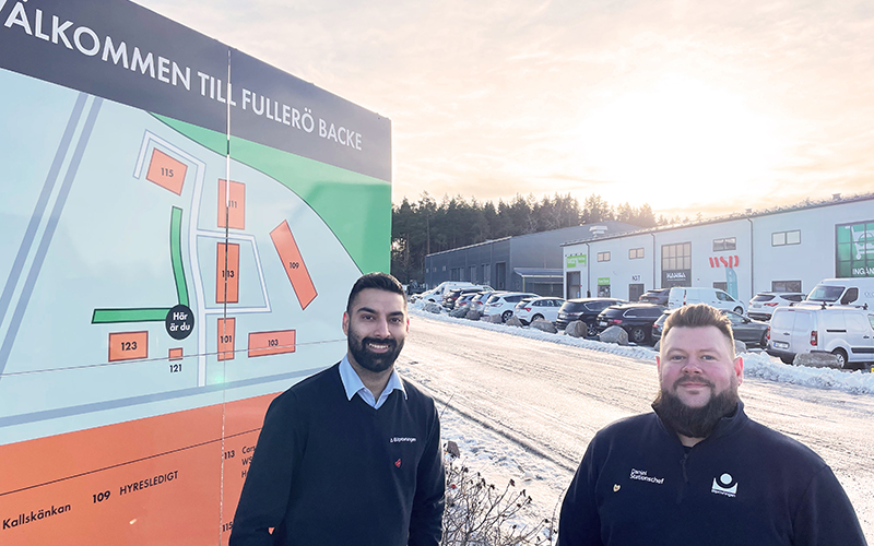 Två bilprovningsanställda står vid en skylt som visar företagsområdet Fulleröbacke.