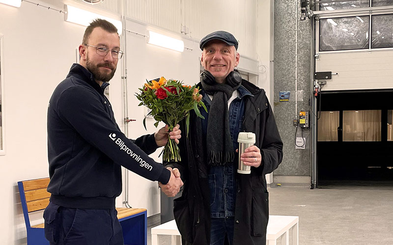 Stationschefen välkomnar den första kunden på den nya stationen Bilprovningen Malmö-Hanö med en bukett blommor.
