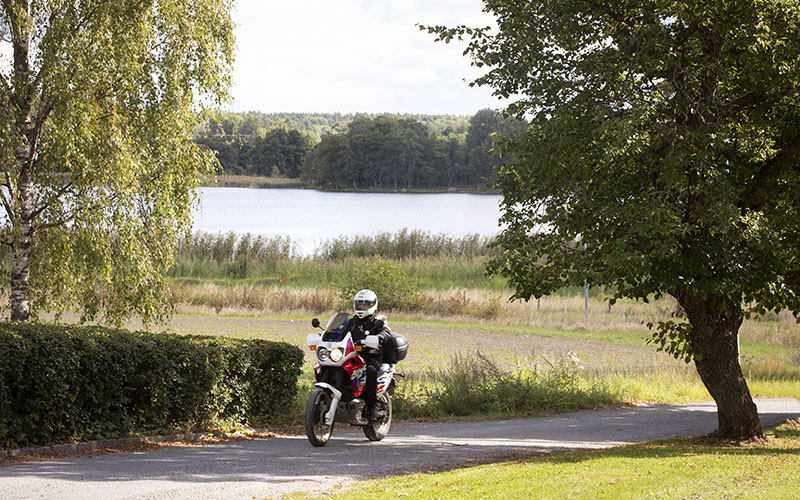 En ensam förare på motorcykel på väg i ett vackert landskap.