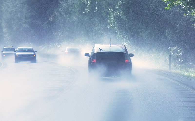 Bilar på väg i ösregn och dålig sikt