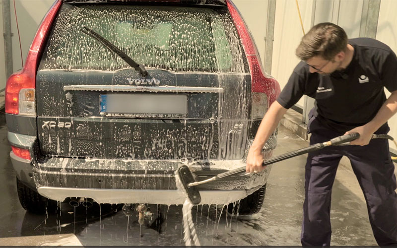 bilprovningsanställd tvättar en bil i en tvätthall